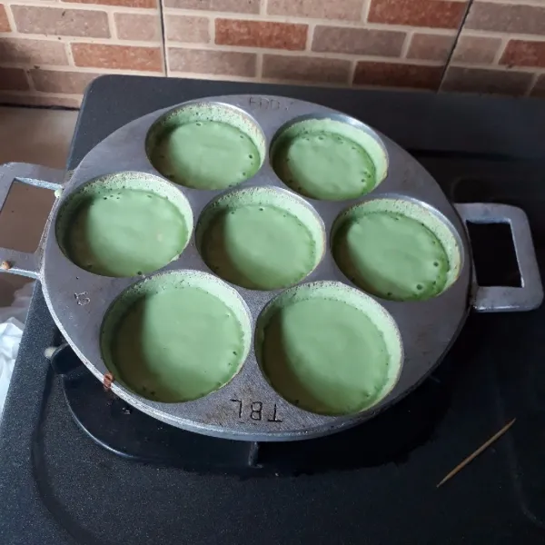 Panaskan cetakan dengan api kecil lalu tuang 1 sendok sayur kecil adonan dan tekan bagian tengah agar membentuk pinggiran. Masak hingga adonan berlubang-lubang lalu tutup cetakan.