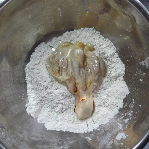 Masukkan paha ayam yang sudah terbalut adonan basah ke dalam wadah berisi tepung kering. Aduk rata dan balut hingga semua bagian paha ayam tertutupi tepung. Angkat.