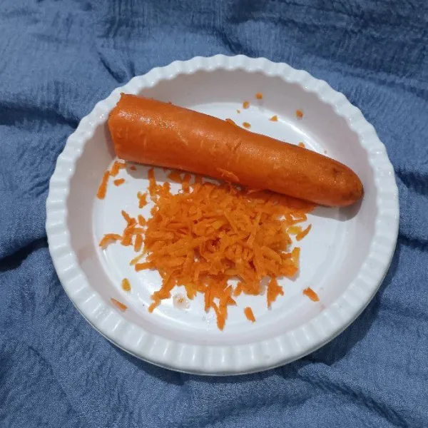 Parut wortel menggunakan parutan keju. Sisakan sedikit.