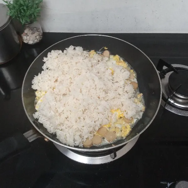 Masukkan nasi, aduk kembali hingga tercampur merata.