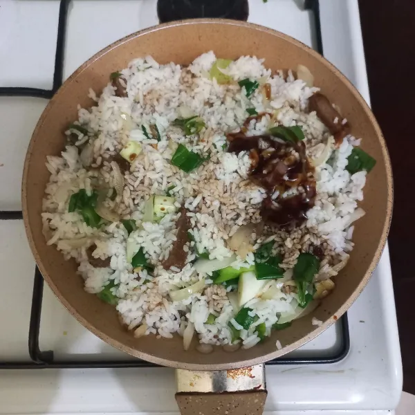 Beri kecap asin, saus tiram, kecap ikan, kecap manis dan minyak wijen, aduk rata kemudian koreksi rasa, masak hingga nasi goreng matang.