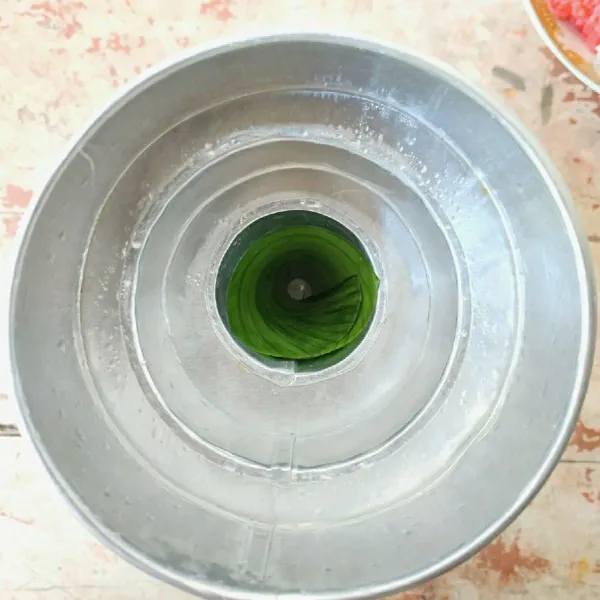 Siapkan cetakan tumpeng, oles tipis dengan minyak dan jangan lupa bagian ujungnya diberi daun agar mudah saat dilepas atau tidak lengket.