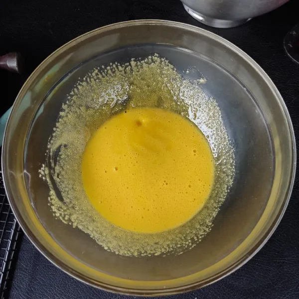 Masukkan ke dalam wadah, kuning telur dan 60 gram gula pasir aduk rata hingga gula larut