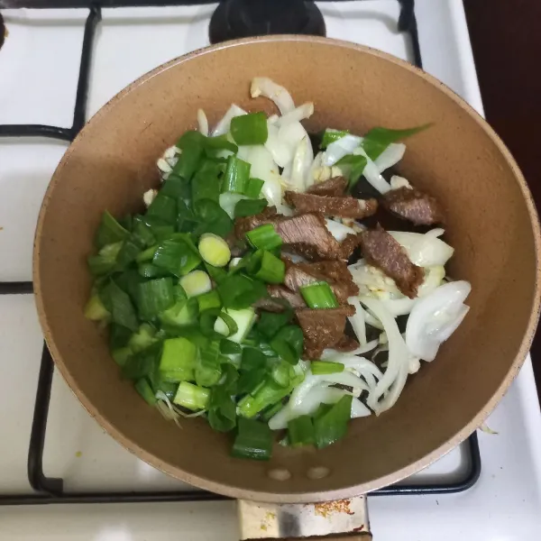 Masukkan irisan daging sapi dan daun bawang, aduk rata.