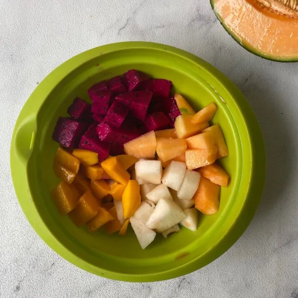 Kupas dan potong buah naga, melon, mangga dan pir.