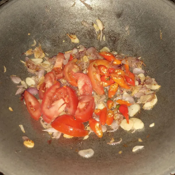 Tumis bawang putih dan bawang merah sampai layu. Tambahkan cabe dan tomat merah lalu masak sampai matang.