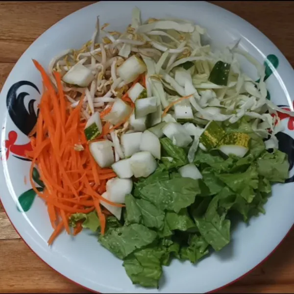 Susun semua sayuran di piring, beri tahu putih, kacang tanah dan kerupuk di atasnya. Lalu berikan kuah asinan di sekitarnya.