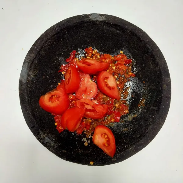 Haluskan bahan sambal dan beri irisan tomat merah kemudian ulek.