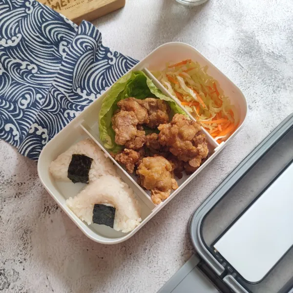Tata di dalam wadah bento, tiriskan salad, kemudian tata di dalam kotak bekal, salad, chicken karage dan onigiri.
