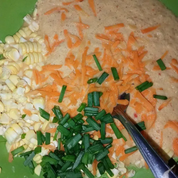 Tuang kedalam wadah berisi sisa bagian jagung, masukkan wortel yang sudah diserut dan potongan daun bawang.