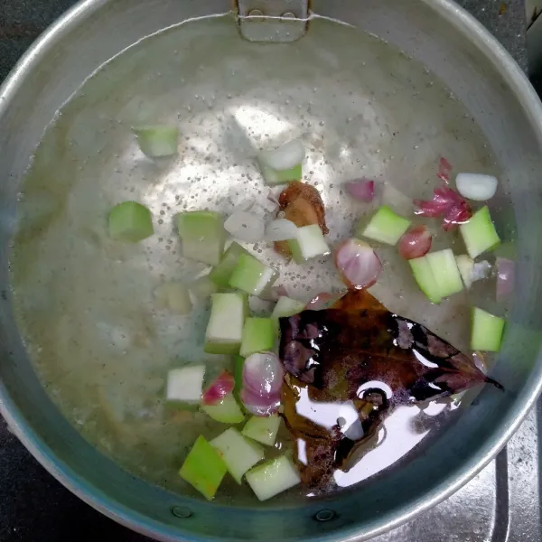 Masukkan labu siam, irisan bawang merah, bawang putih, lengkuas dan daun salam.