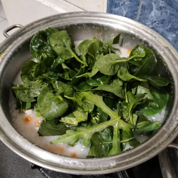 Setelah itu masukkan daun gedi, daun kunyit, daun bayam brazil, dan daun kangkung. Aduk sampai layu.
