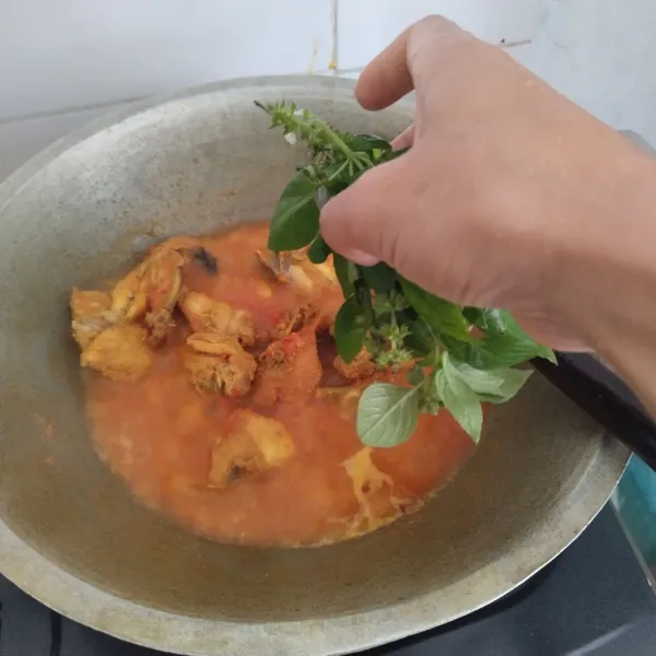 Tunggu hingga bumbu meresap sempurna pada daging ayam dan air mulai menyusut, kemudian masukkan daun kemangi, kecilkan api kompor dan aduk sebentar kemudian angkat dan sajikan.
