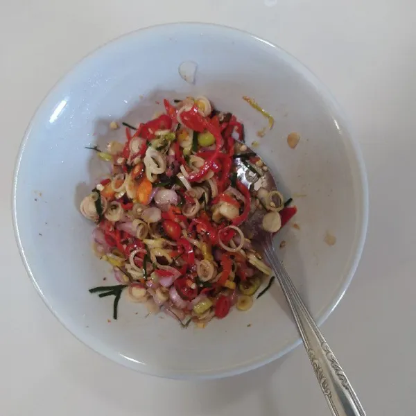Siram sambal dengan minyak panas, tambahkan garam, gula dan lada bubuk lalu aduk rata.