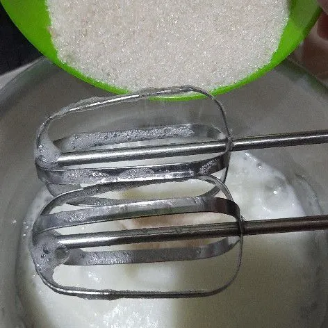 Masukkan gula pasir sedikit demi sedikit sambil di kocok hingga menjadi adonan kental berjejak. Kemudian tambahkan garam