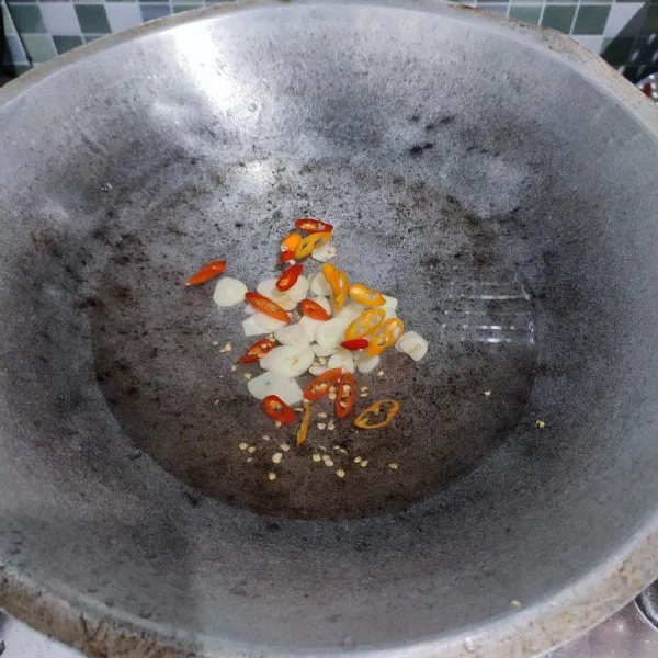 Masukkan air ke dalam wajan. Tambahkan bawang putih dan cabe rawit, biarkan mendidih.