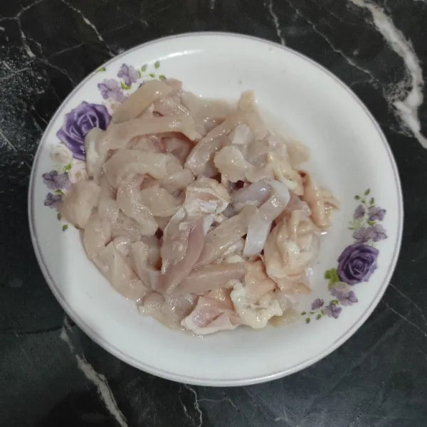 Potong memanjang daging ayam yang sudah dibersihkan.