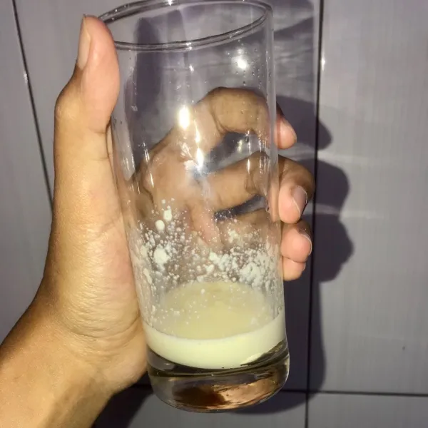 Larutkan susu bubuk dengan air kedalam gelas saji.