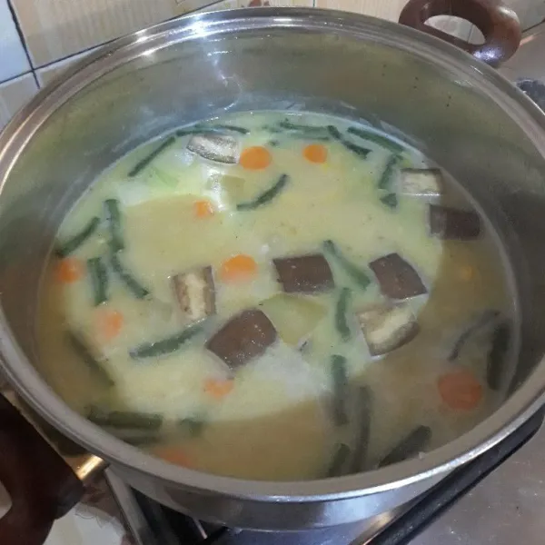 Tambahkan santan, terong, dan kacang panjang. Bumbui dengan garam, kaldu bubuk dan gula. Aduk rata dan koreksi rasa.