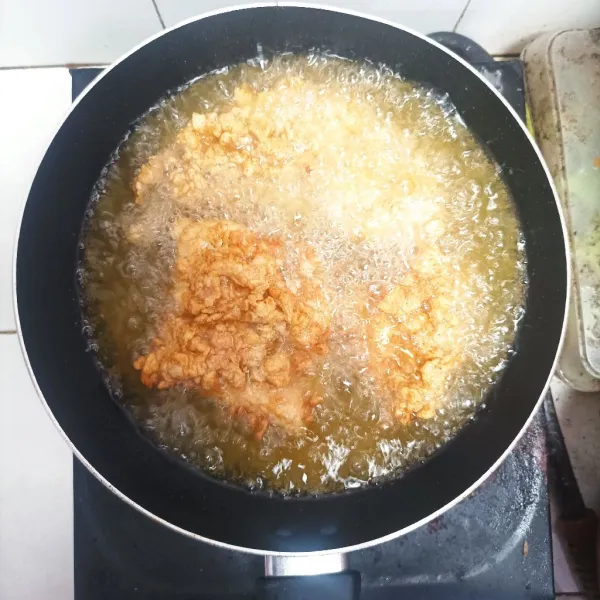 Goreng ayam dengan minyak panas, hingga sedikit menguning. Lalu angkat. Diamkan selama 5 menit dan goreng kembali selama hingga berwarna keemasan.
