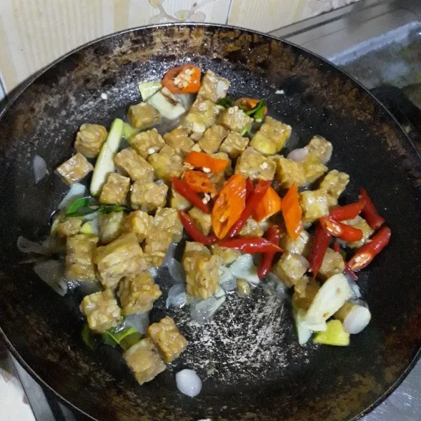 Masukkan tempe goreng, air, cabe kriting merah dan cabe rawit merah. Aduk rata.