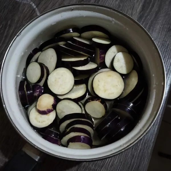 Potong terong bentuk bulat, rendam air agar terong tidak berubah warna.