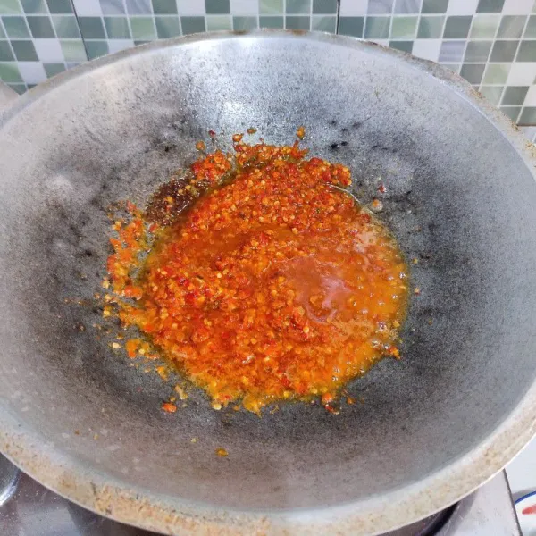 Haluskan cabe merah, cabe rawit serta bawang merah, kemudian tumis dengan sisa minyak menggoreng ikan hingga wangi.