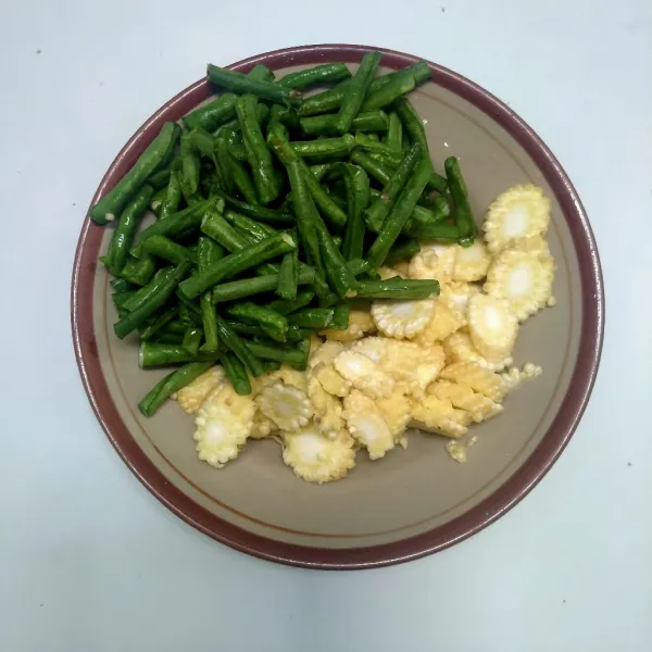 Siapkan bahan. Potong-potong kacang panjang dan iris tipis baby corn.