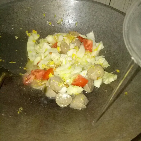 Setelah telur setengah matang, masukkan kubis, bakso, tomat dan air. Masak sampai kuah mendidih.