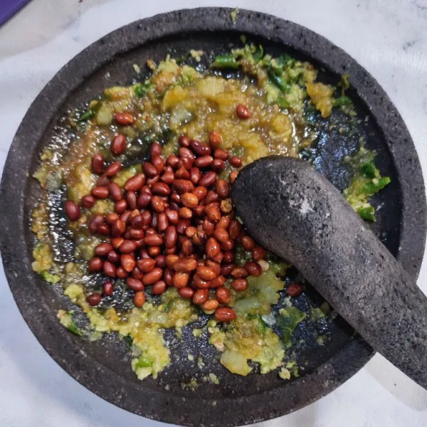 Masukkan kacang tanah, ulek. Tambahkan air panas secukupnya sesuai tingkat kekentalan yang diinginkan.