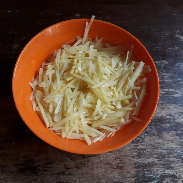 Kupas kentang dan potong bentuk korek api tipis. Campurkan dengan garam, diamkan selama 10 menit, lalu cuci bersih dan tiriskan