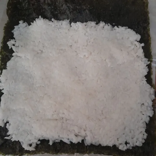 Setelah itu siapkan nori dan pipihkan nasi di atas nori sisihkan bagian ujung nori.
