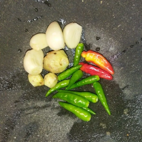 Siapkan cabe rawit hijau, cabe rawit merah, bawang putih dan kencur, lalu ulek bersama garam dan kaldu bubuk.