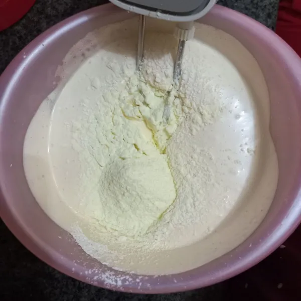 Tambahkan baking powder, susu bubuk, dan ayakan tepung terigu, lalu kocok rata