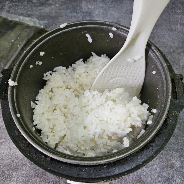 Masak nasi sesuai takaran memasak nasi pulen. Setelah matang campurkan nasi dengan mirin dan garam, lalu aduk hingga rata.