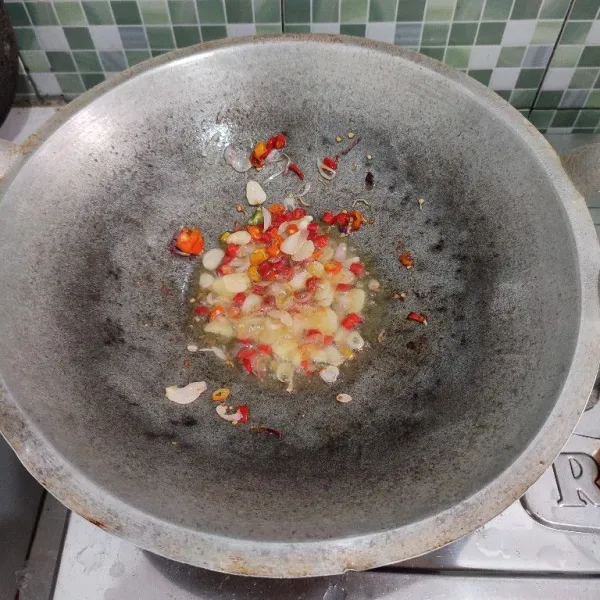 Tumis bawang merah, bawah putih, cabe rawit, serta cabe merah hingga wangi dan layu.