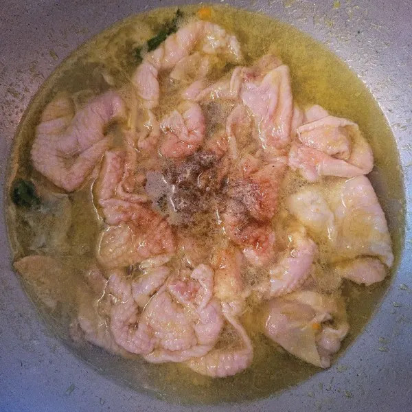 Tambahkan bumbu seperti penyedap rasa, garam, dan lada bubuk, aduk hingga tercampur, dan ungkep kulit ayam selama 15 menit.