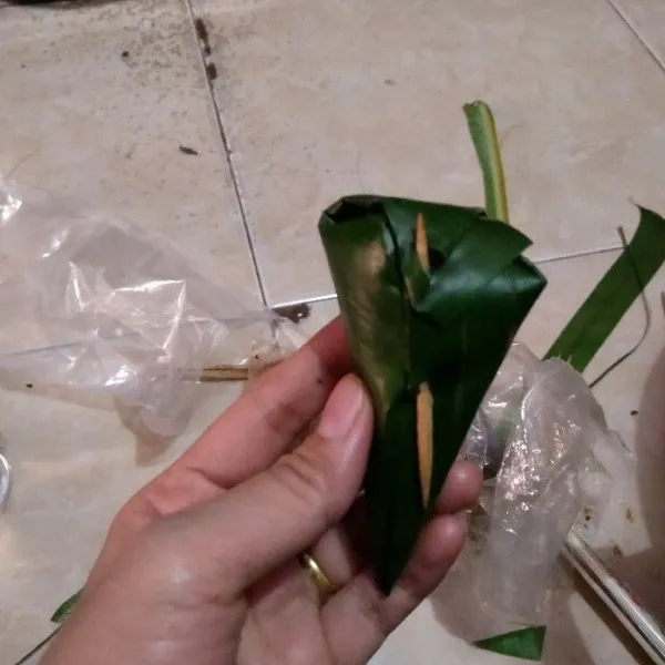 Lalu bungkus, rapatkan dan sematkan lidi supaya daun tidak lepas.