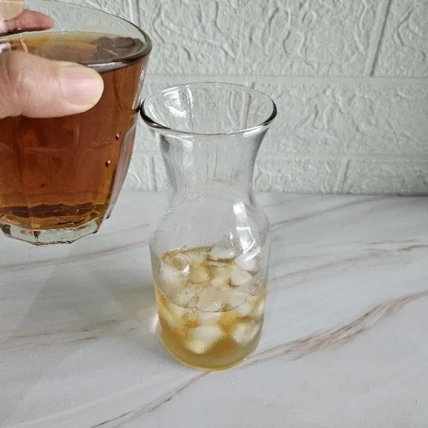 Siapkan gelas saji, masukkan ice cube lalu tuang teh ke dalam gelas.