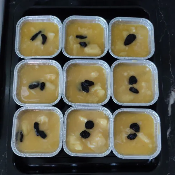 Tuang adonan kedalam cup aluminium foil lalu beri topping kismis.