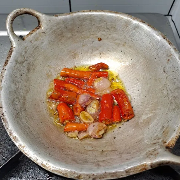 Goreng bawang merah, cabe merah dan cabe rawit sampai layu. Angkat dan taruh di atas cobek.