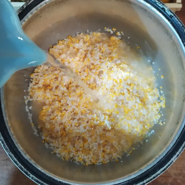 Campur beras jagung dengan beras putih lalu cuci. Masukkan ke magic com, tambahkan air lalu masak seperti biasa.