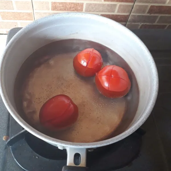 Kerat bagian atas tomat. Masak dalam air mendidih selama 30 detik, tiriskan.
