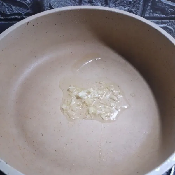 Masukkan bawang putih dan minyak ke dalam wajan.