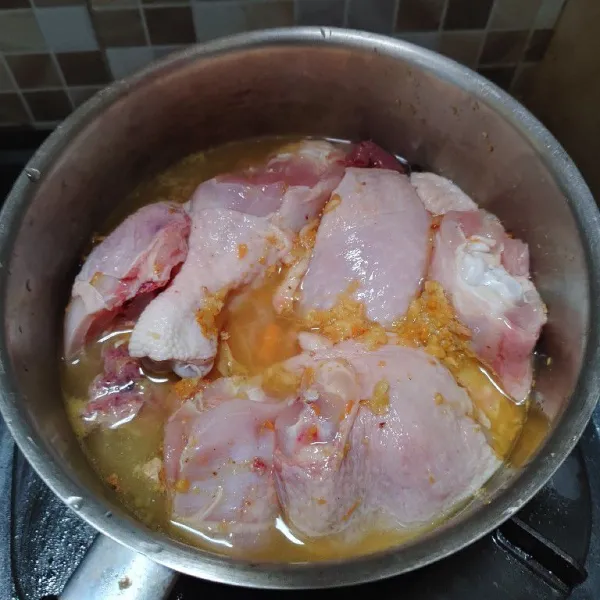 Tata ayam di panci, beri bumbu yang sudah dihaluskan dan tambahkan air secukupnya. Ungkep ayam sampai matang.