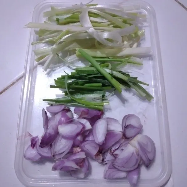 Iris semua bawang merah dan daun bawang, pisahkan bagian batang putih dan hijaunya lalu iris tipis memanjang.