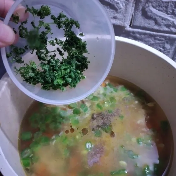 Tambahkan kaldu bubuk, lada bubuk, dan cincangan parsley segar, aduk, koreksi rasa