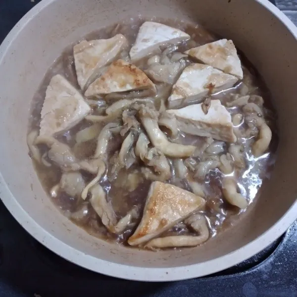 Tambahkan kaldu dan lada bubuk. Masak hingga bahan kecap meresap ke dalam tahu dan jamur