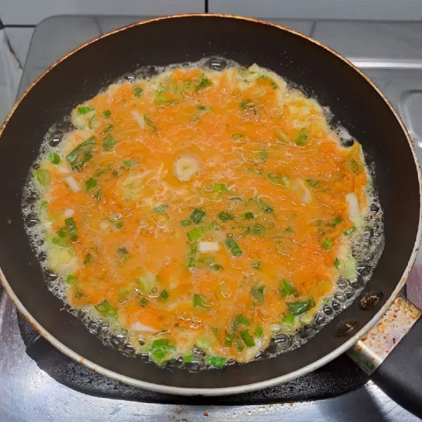 Panaskan teflon dengan sedikit minyak goreng. Tuang adonan telur dan ratakan. Tunggu sampai bagian bawah berkulit.