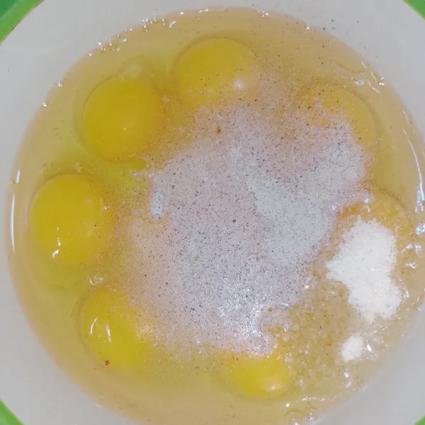 Dalam wadah, masukkan telur, garam, kadu bubuk, dan lada bubuk, lalu kocok lepas